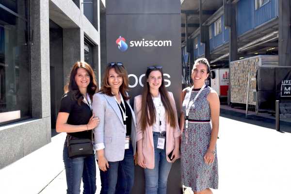 A group of women smiling in front the Swisscom building